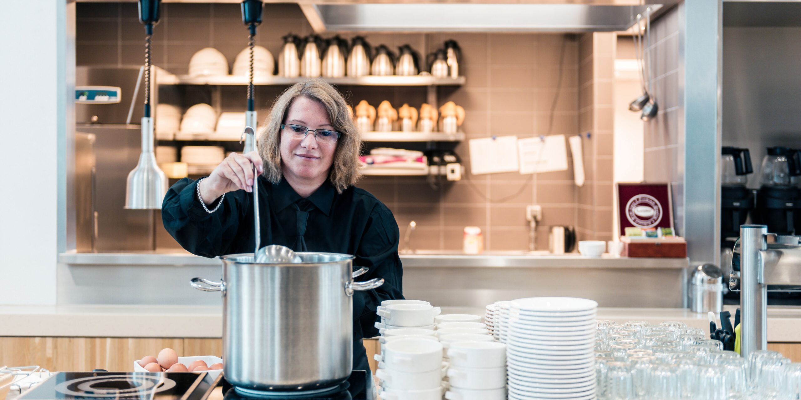 Cateringmedewerkster van PCH Dienstengroep schept soep op